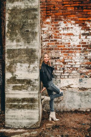 Urban portrait session against textured brick and concrete wall backdrop.