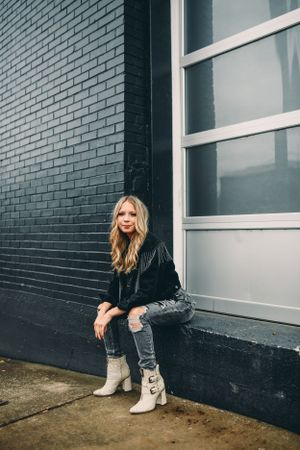 Modern fashion shoot against dark painted brick wall and white paneled windows.