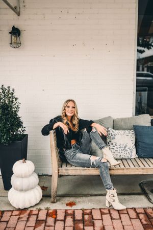 Autumn scene with white pumpkins and cozy porch seating against white brick wall.