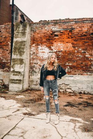 Fashion photo shoot against weathered brick wall showing distressed denim style.