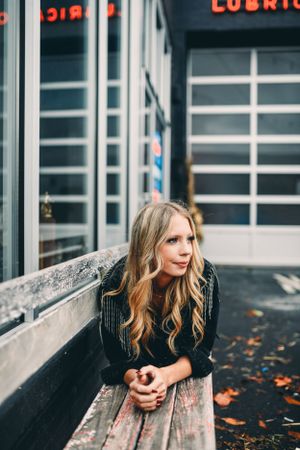 Urban fashion photography with autumn leaves against industrial building exterior.