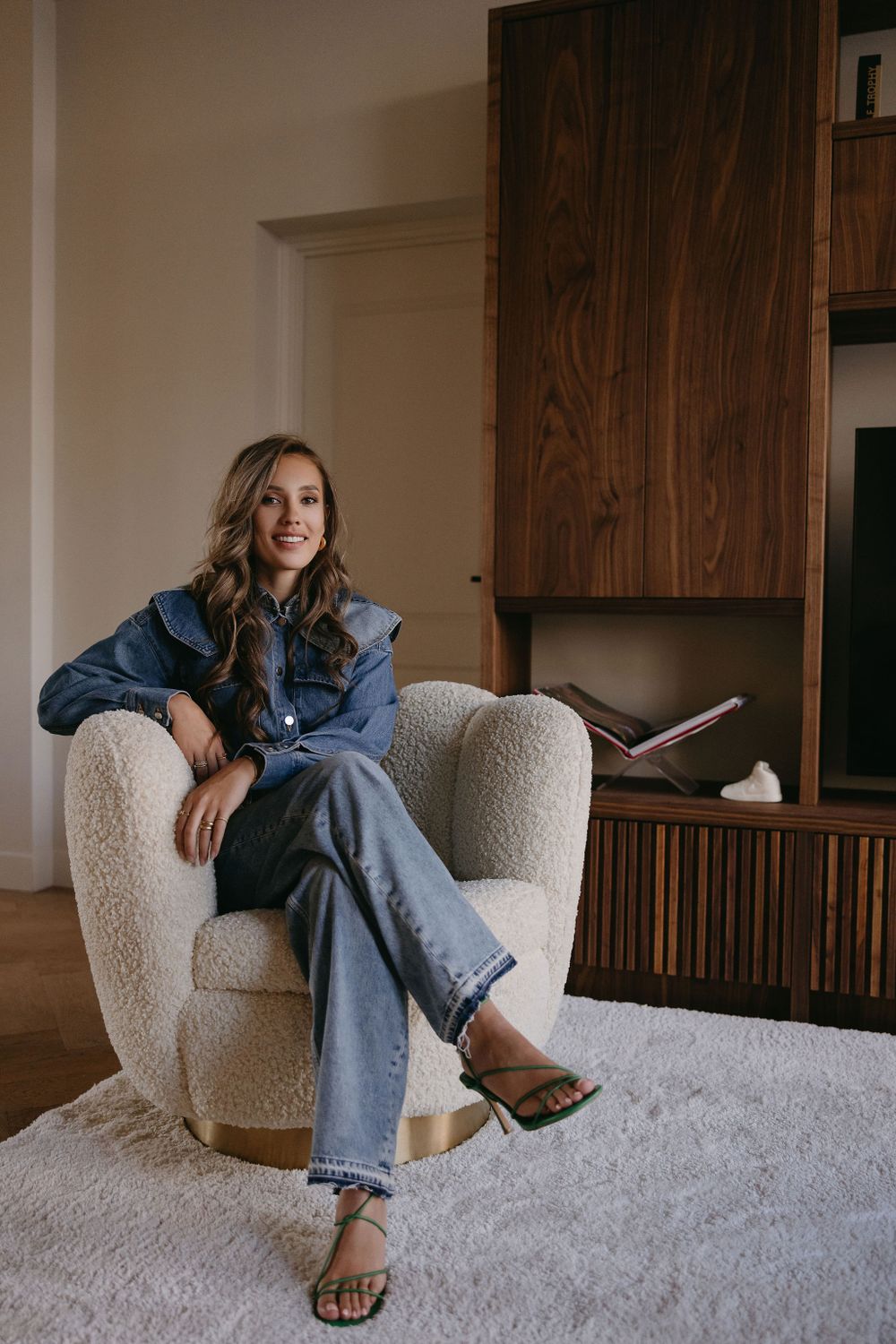 Casual lifestyle photo showing person relaxing in denim outfit on cream armchair.