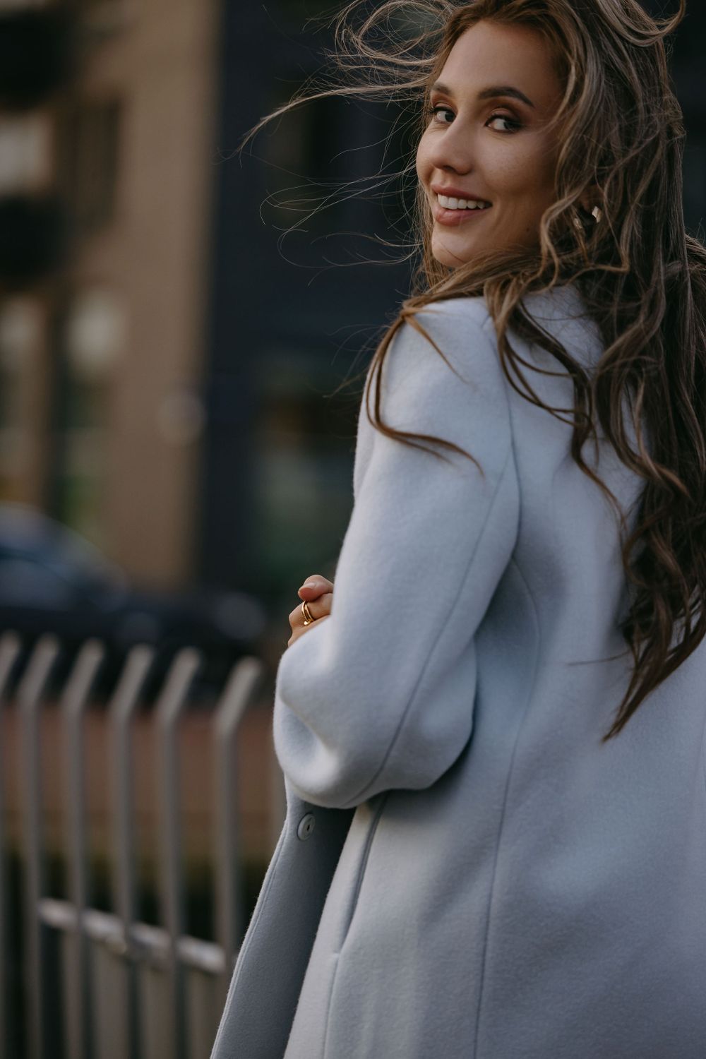 Wind-swept portrait showing joyful expression and light colored winter coat.