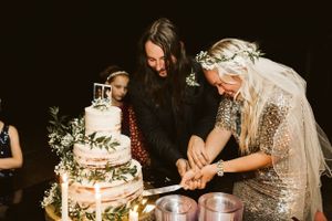 Wedding cake cutting celebration with sparklers and guests gathered around in dark setting.