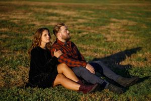 Beautiful married couple sitting in a field during Christmas family photoshoot