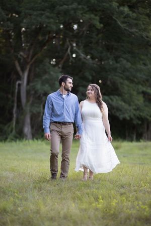 Engaged couple walking through a field