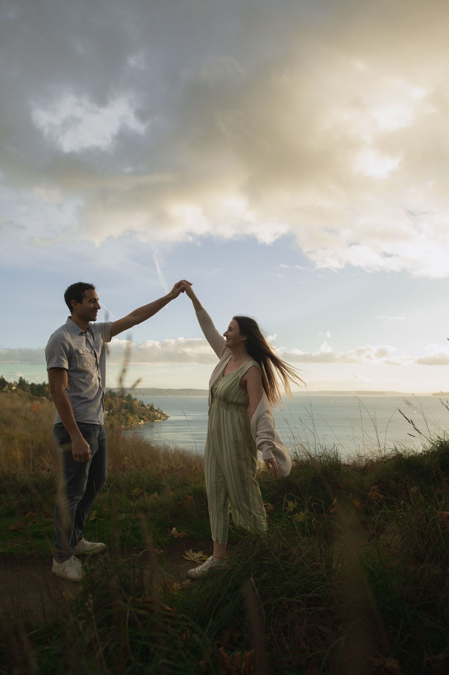 Dancing couple silhouetted against dramatic coastal sunset sky.
