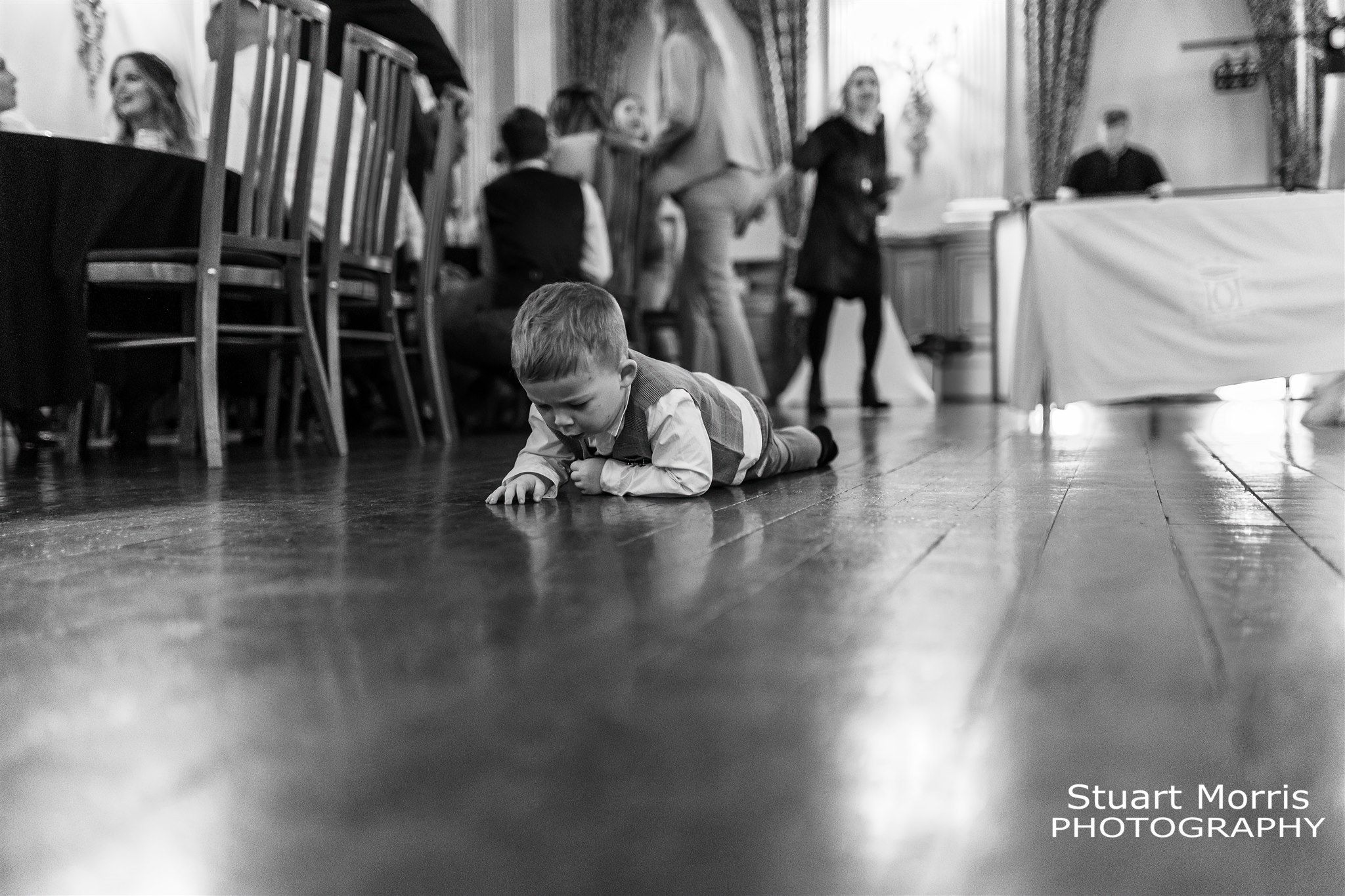 Bride and grooms young son crawls on his stomach army style across the Knowsley hall dance floor.
