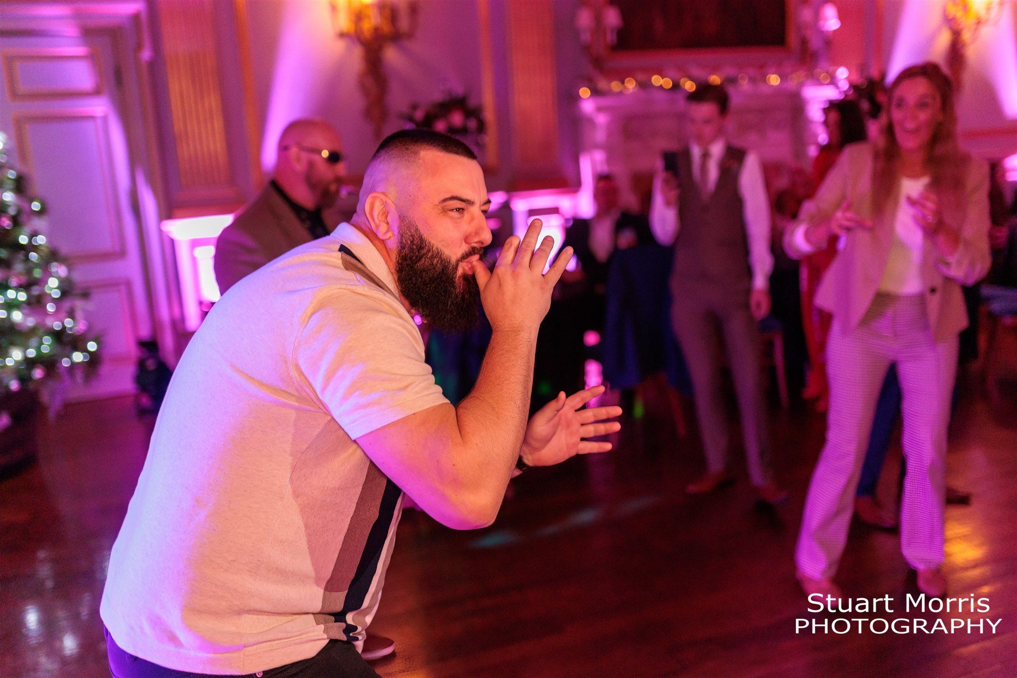 Wedding guest plays the air saxophone on the dance floor at Knowsley hall. Liverpool wedding photographs.
