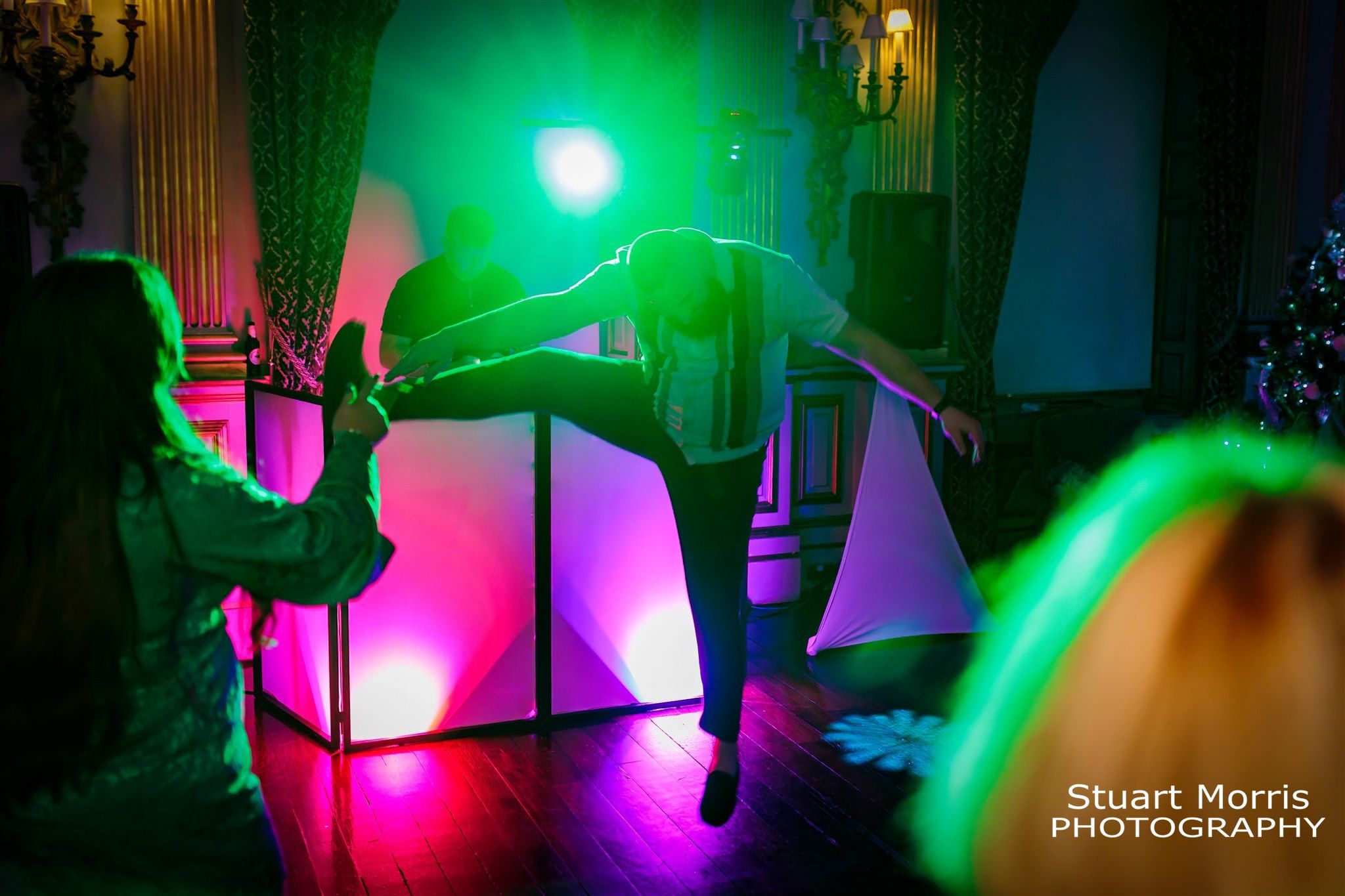 Wedding guest jumps up one leg outstretched and head to he side on the dancefloor at Knowsley hall Liverpool.