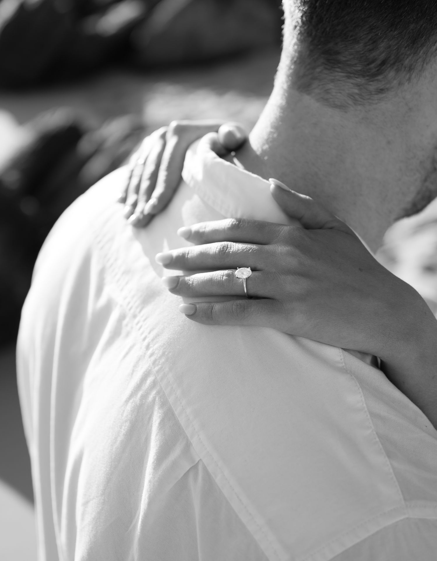 Black and white photo of hands embracing with a wedding ring visible, showing an intimate moment of comfort.