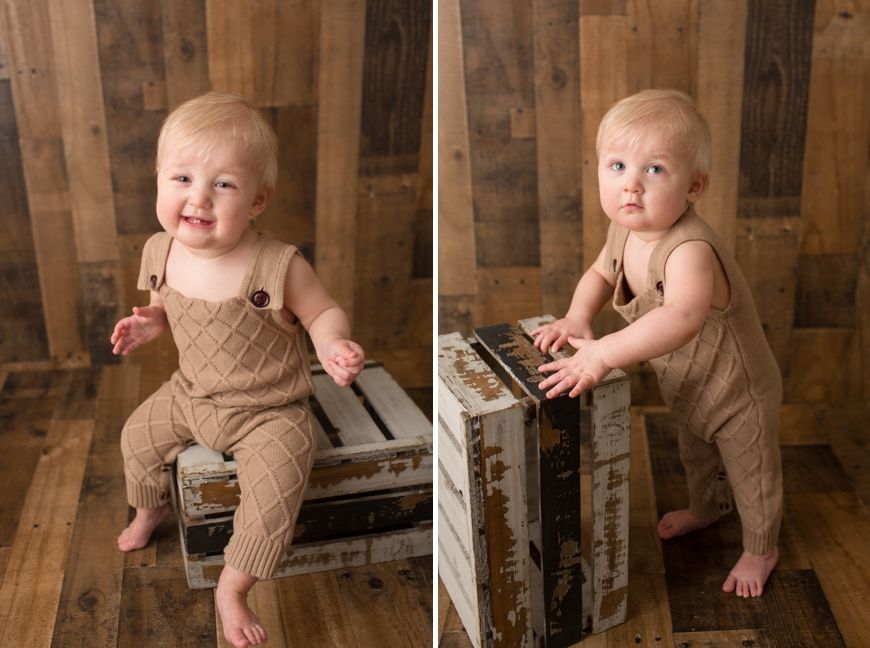 Baby in brown corduroy overalls poses with vintage wooden crates in studio setting.