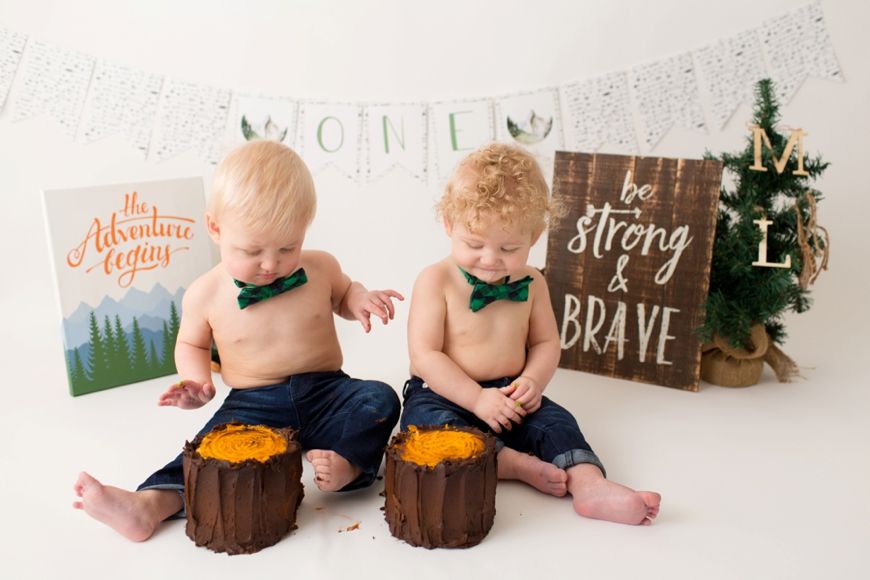 Two babies in navy shorts with smash cakes and holiday decor for a Christmas photoshoot.