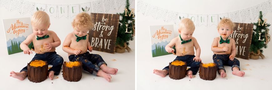 Two children sitting by decorated tree stumps with orange frosted cakes and festive decor.