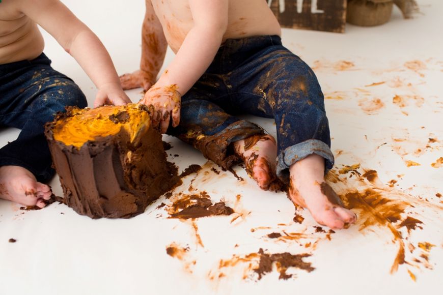 Close-up of messy hands and cake crumbs during a cake smash photoshoot.