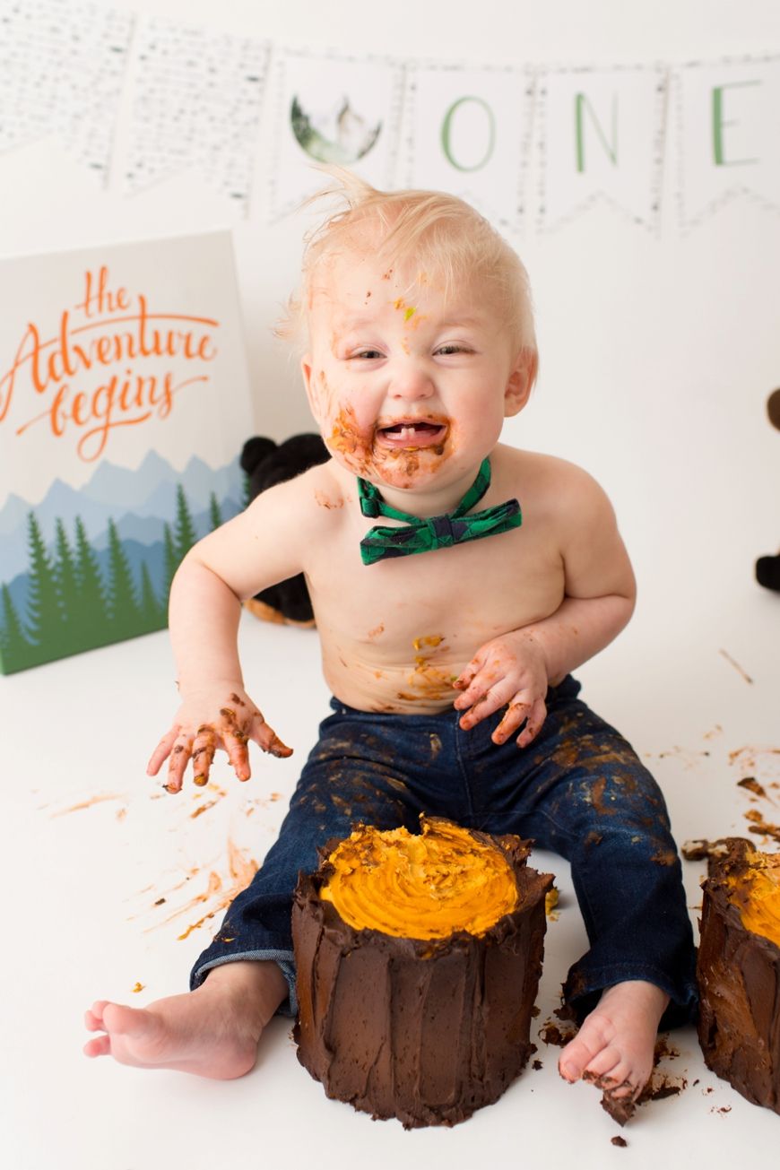 Messy toddler with orange frosting during cake smash photo session.