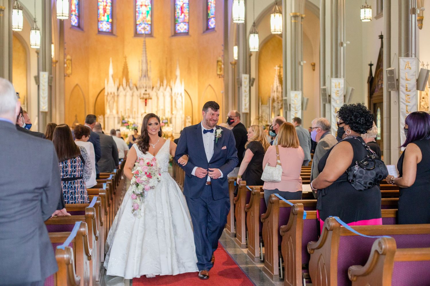 A wedding ceremony takes place in a beautiful church with stained glass windows and ornate architecture.