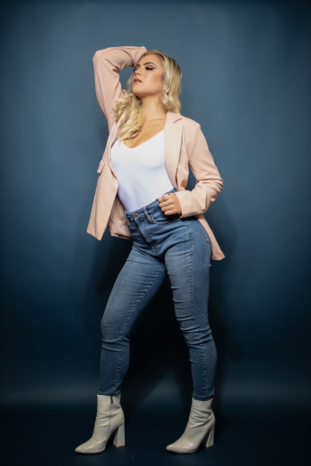 Full length fashion photo showcasing casual chic style with pink blazer and fitted jeans.