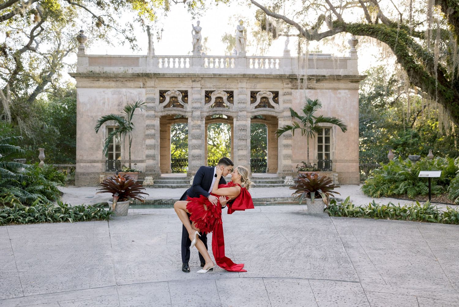 A romantic dance dip pose in front of an elegant stone garden pavilion.