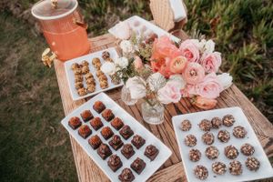 Elegant dessert table with assorted chocolate treats and pink floral decorations.