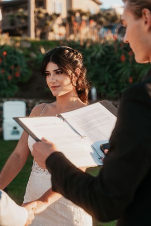 A wedding ceremony participant reviews documents during an outdoor sunset service.