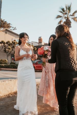 Wedding party members in white and coral dresses celebrate outdoors.
