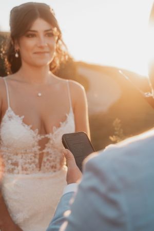 Bride in lace wedding dress during golden hour ceremony with sunlight flare.