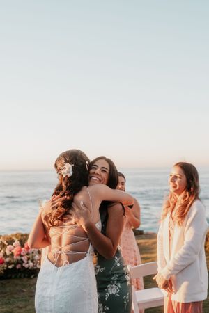 Wedding guests embrace and celebrate during outdoor oceanfront ceremony.