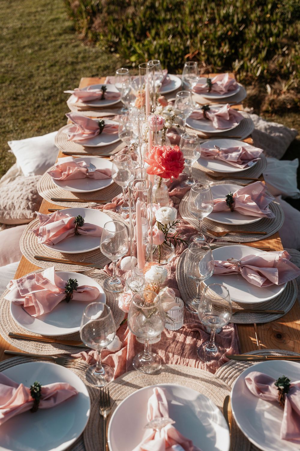 Elegant pink and white wedding reception table setting with crystal glassware and place settings.
