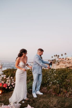 Candid beach wedding moments captured against coastal landscape at sunset.