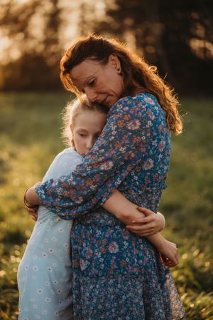 Tender embrace between two people in floral dress and light dress during golden hour.