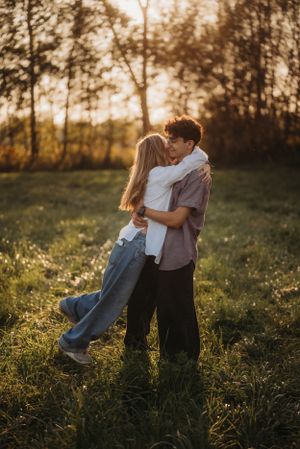 A couple embraces while sharing a romantic moment in a sunlit field.