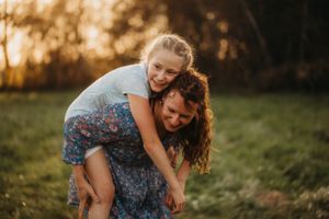 A playful piggyback ride moment photographed in golden hour lighting.