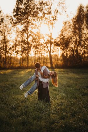 A romantic dip pose photographed against a golden sunset in a meadow.