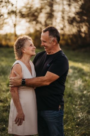 A couple embraces outdoors in warm evening light while sharing an intimate moment.