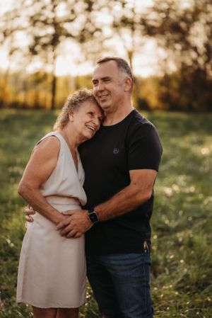 A loving couple shares laughter while embracing in a sunlit meadow during golden hour.