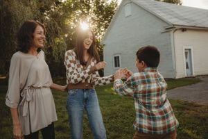 Group of people laughing together outside white building during golden hour.