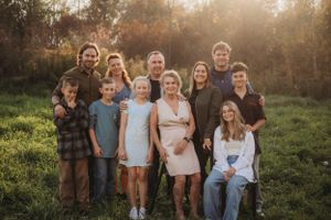 Large family group portrait of multiple generations posing together outdoors at sunset.
