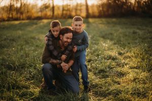 A joyful family moment captured during golden hour in a grassy field.