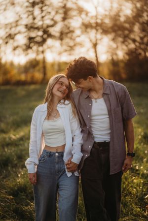 A young couple shares a tender moment while holding hands in golden evening light.