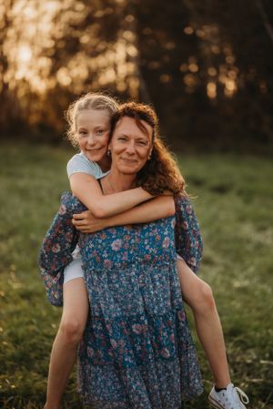 A heartwarming outdoor portrait during sunset with backlit figures sharing a playful piggyback ride.
