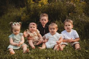 Group of young children sitting together on grassy hill for portrait.