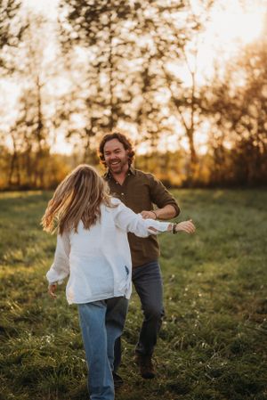 A couple dances together in a sunlit meadow during golden hour.