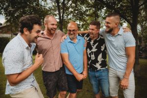 Group of men laughing together during outdoor family gathering.
