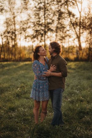 Romantic couple sharing an intimate moment in a sunlit field wearing casual attire.