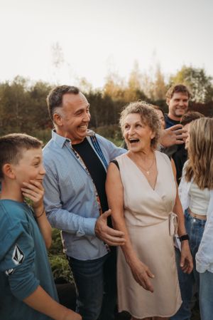 Multi-generational family sharing genuine laughter during outdoor photo session.