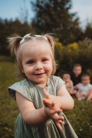 Toddler in mint green dress smiling at camera with pigtails.