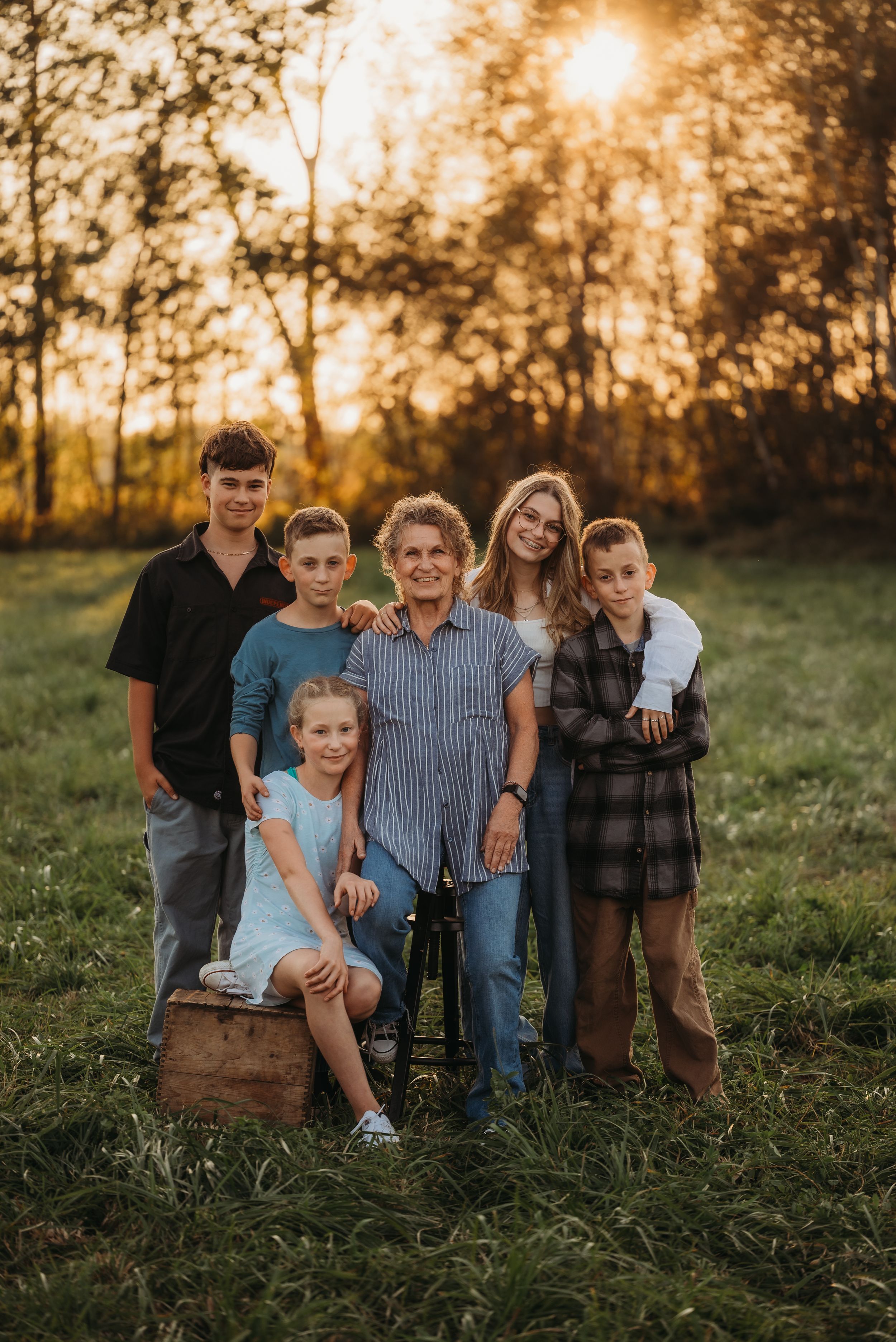 A family group portrait in a field at sunset with beautiful golden backlighting.