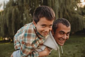 A joyful piggyback ride moment captured outdoors with warm lighting.