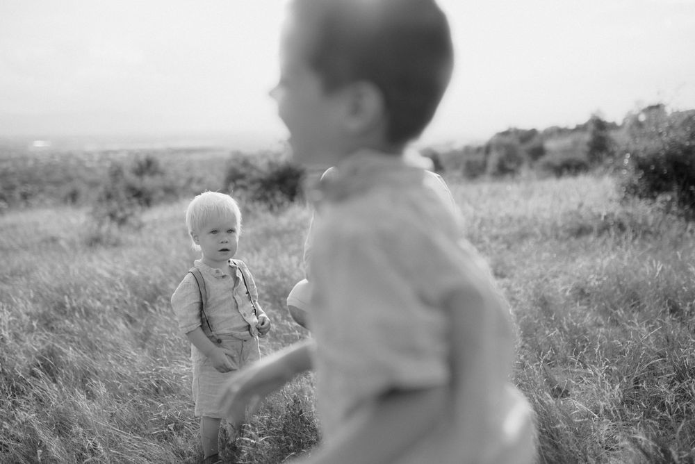Black and white photo of two young children playing together in a grassy outdoor field.
